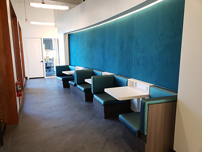Blue-upholstered booth-style seating sits in a well-lit alcove off a CGL hallway.